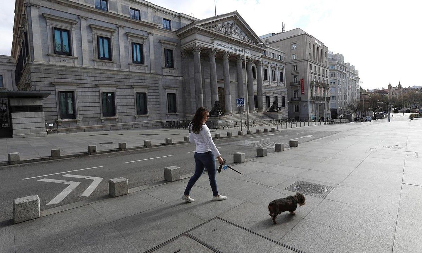 Madrilgo kaleak hutsik: emakume bat zakurra paseatzen Espainiako Gorteen aurrean. KIKO HUESCA / EFE.