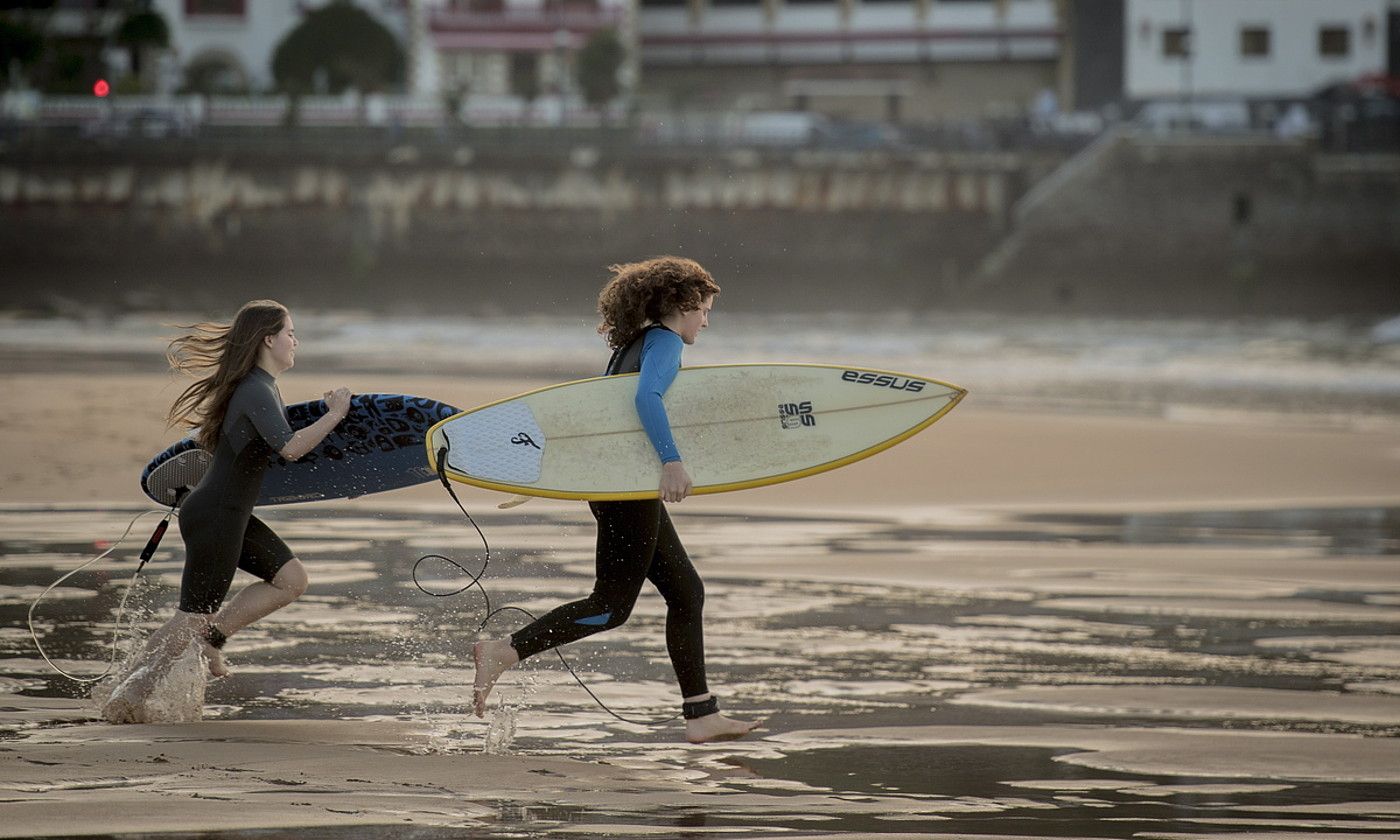 Bi surflari, lasterka, oholak besapean hartuta, Zarauzko hondartzan. GORKA RUBIO / FOKU.