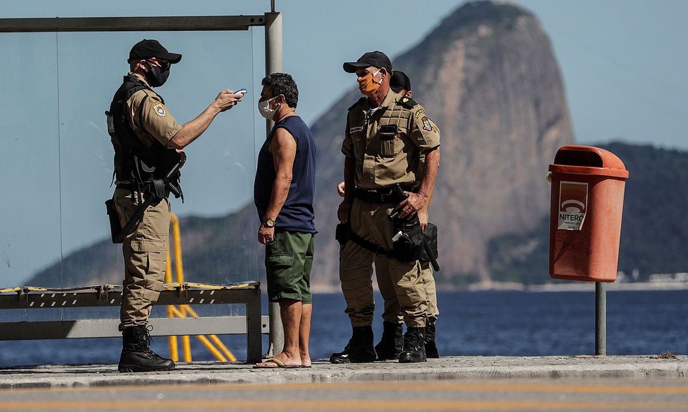Segurtasun indarretako agenteak gizon bati tenperatura hartzen, Brasilen. ANTONIO LACERDA / EFE.