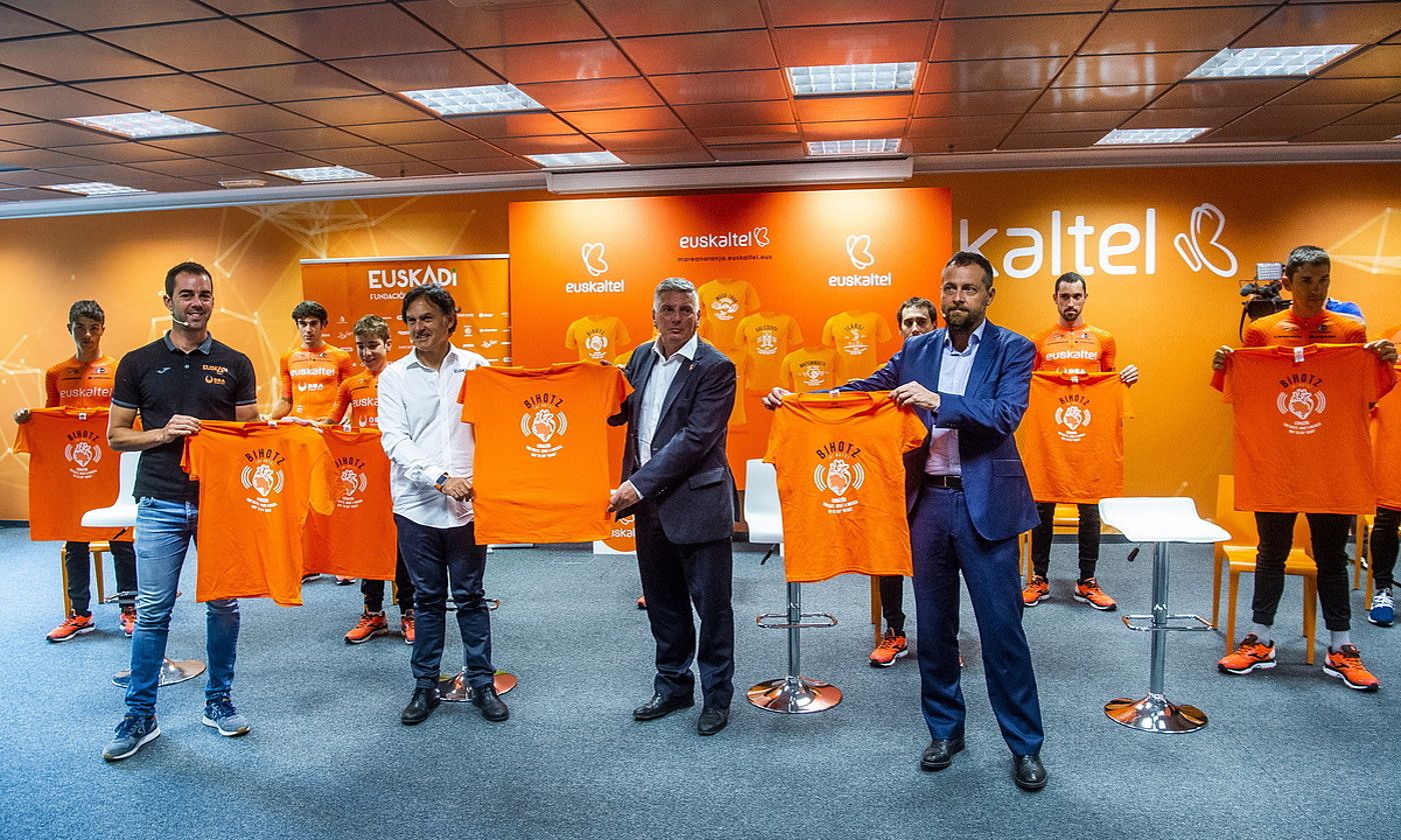 Euskaltel enpresako eta Euskaltel-Euskadi taldeko ordezkariak, preseski egindako zortzi elastiko laranjak erakusten, atzo, Derion. LUIS JAUREGIALTZO / FOKU.