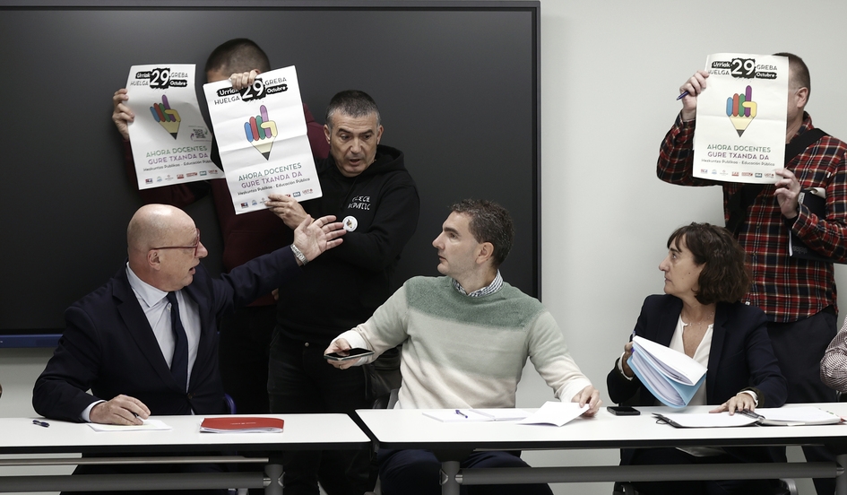 Sindikatuetako kideak, gaur, hilaren 29ko greba iragartzeko kartelak astintzen, Carlos Gimeno kontseilariaren aurrean. JESUS DIGES/EFE