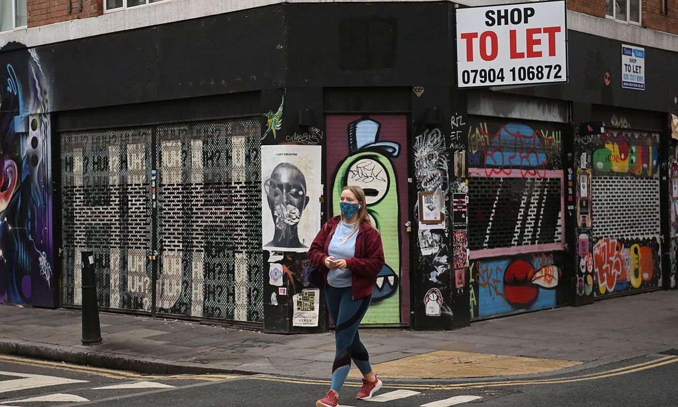 Emakume bat itxitako denda baten aurretik igarotzen, atzo, Londresen. NEIL HALL / EFE.