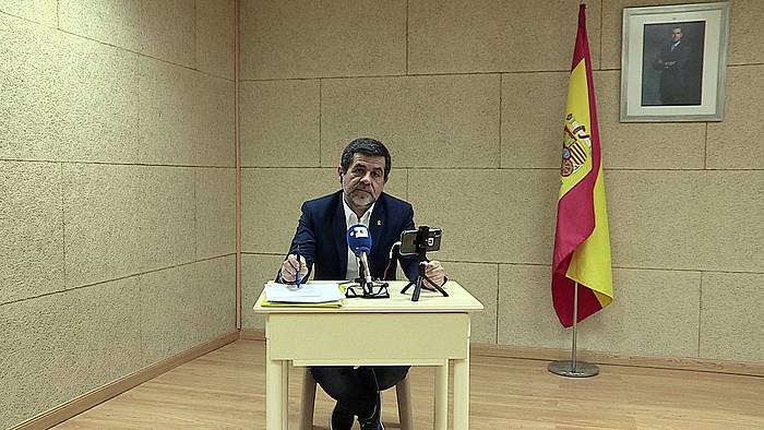 Jordi Sanchez, Espainiako bandera eta erregearen argazkia atzean dituela. EFE
