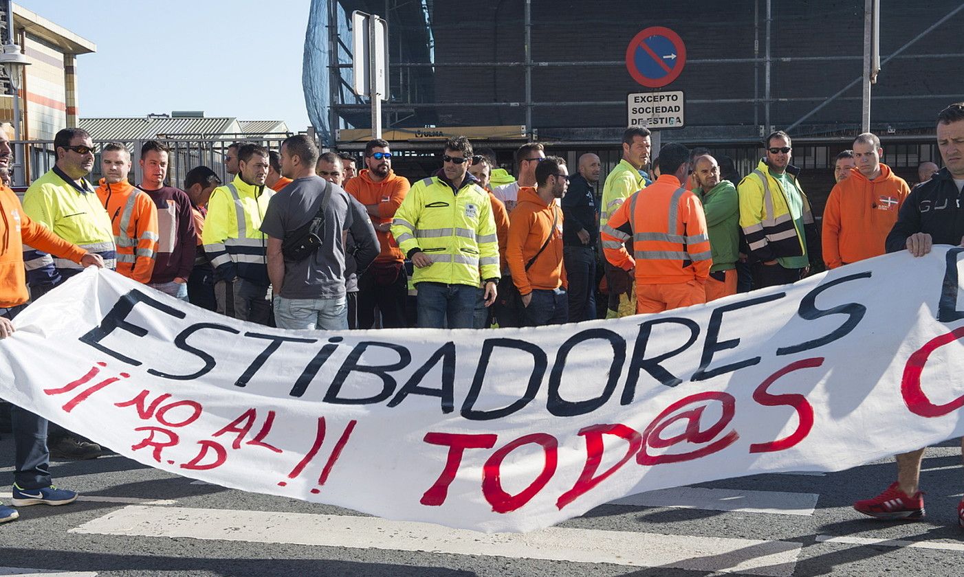 Bilboko portuko bi zamaketari pankarta bat tolesten protesta elkarretaratze baten ondoren. MONIKA DEL VALLE / FOKU.