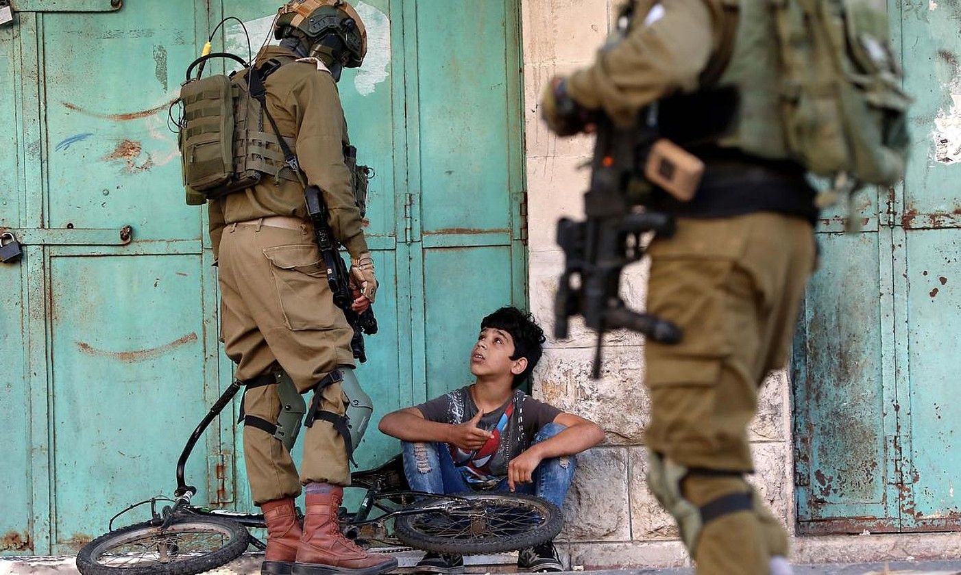 Israelgo soldaduak haur bat galdekatzen, Hebronen (Palestina). ABED AL HASHLAMOUN / EFE.