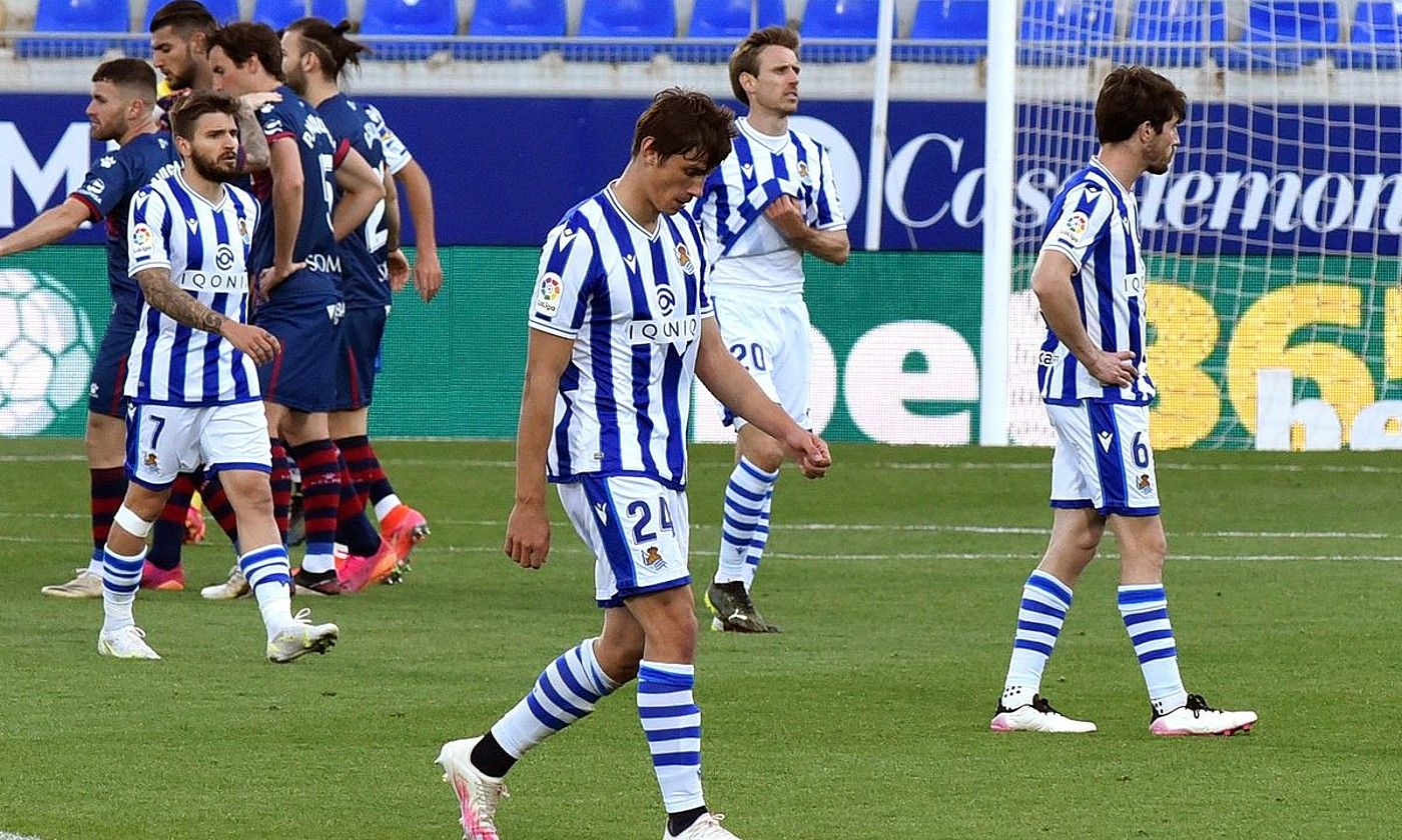 Realeko hainbat jokalari burumakur, eta atzean, Huescakoak, pozarren, atzoko gol bakarra sartu berritan. JAVIER BLASCO / EFE. Realeko hainbat jokalari burumakur, eta atzean, Huescakoak, pozarren, atzoko gol bakarra sartu berritan. JAVIER BLASCO / EFE.