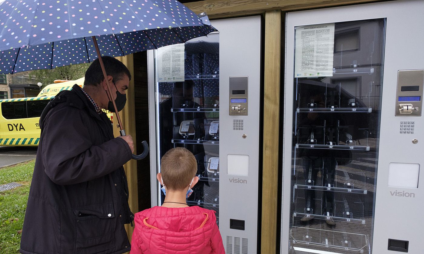 Langile ikastetxeko haurrak, ontziak pisatu, etiketak jarri eta garraiatzen. Aldamenean, bi lagun zero zaborreko hozkailu bati begira. JON URBE / FOKU.