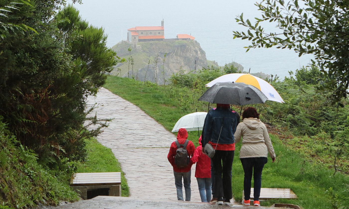 Familia bat Urizarreta eta Ermu arteko ibilbide zirkularra egiten, atzo goizean. Atzean, Gaztelugatxeko ermita. OSKAR MATXIN / FOKU.