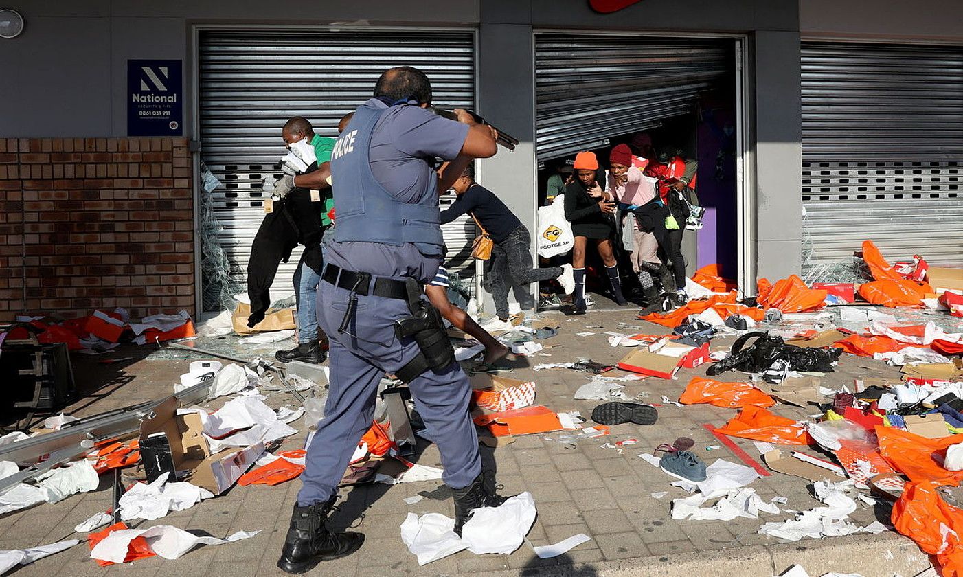 Hegoafrikako polizia bat, arma Nikeren Durbango denda batean sartu ziren herritar batzuei begira jartzen, iragan astelehenean. EPA / EFE.