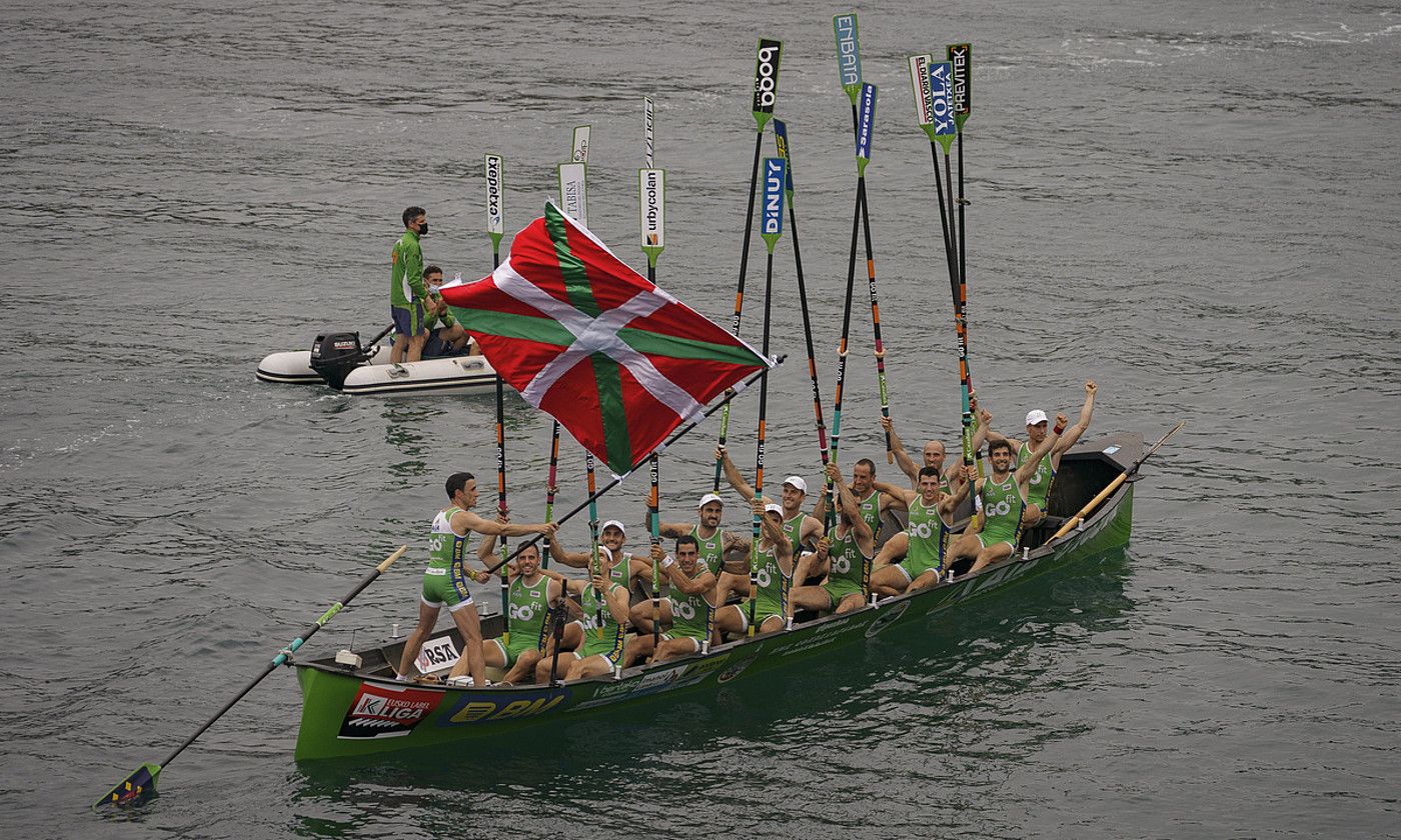 Ioseba Amunarriz Hondarribiko patroia, Euskadiko Txapelketako bandera zazpigarren aldiz astintzen; arraunlariak arraunak goran dituztela. Haien atzean, Mikel Orbañanos entrenatzailea, atzo, Lekeition, Bizkaian. ARITZ LOIOLA / FOKU.