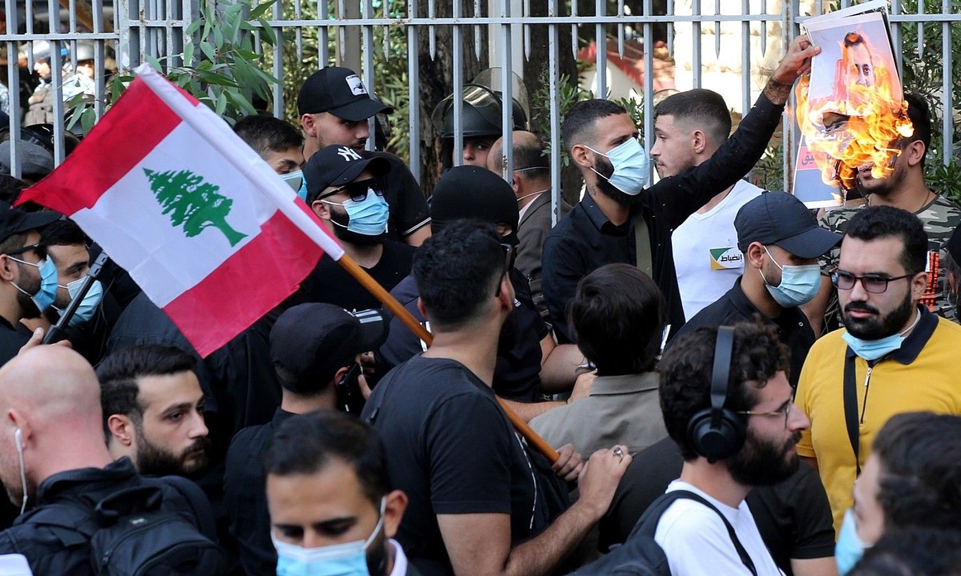 Militante xiitak, atzo Beiruten egindako manifestazioan. Horietako bat, Tarek Bitar epailea azaltzen den argaki bati su ematen. NABIL MOUNZER / EFE.