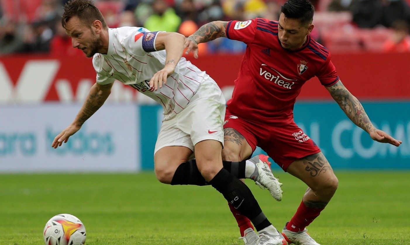 Chimy Avila Osasunako jokalaria eta Ivan Rakitic Sevillakoa, lehian, atzo, Sanchez Pizjuanen, ligako partidan. JULIO MUÑOZ / EFE. Chimy Avila Osasunako jokalaria eta Ivan Rakitic Sevillakoa, lehian, atzo, Sanchez Pizjuanen, ligako partidan. JULIO MUÑOZ / EFE.