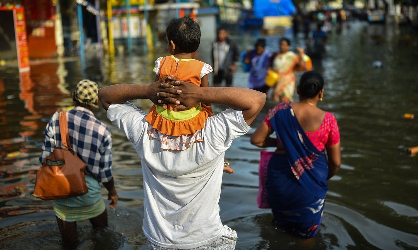 Indiako gizon bat alabarekin, urez gainezka egindako kaleetan, Chennai hirian, iazko azaroan. I. MOHAMMED / EFE. Indiako gizon bat alabarekin, urez gainezka egindako kaleetan, Chennai hirian, iazko azaroan. I. MOHAMMED / EFE.