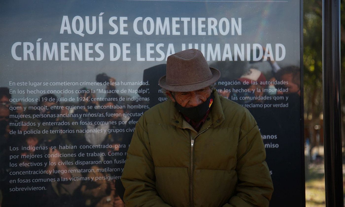 Gizon indigena bat, Napalpiko Sarraskia azaltzen duen kartel baten paretik pasatzen, Argentinako Napalpi herrian. BERRIA.