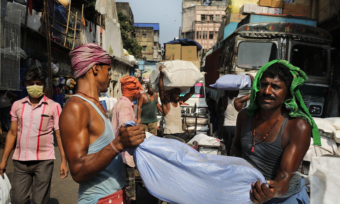 Langile batzuk zakuak jasotzen, egun bero batean, Kolkatan, Indian. EFE.