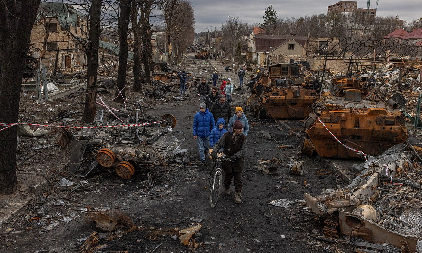 Butxako zenbait zibil herriko kale batean, Errusiako tropen ibilgailuak bazterrean direla, Kievetik gertu. ROMAN PILIPEY / EFE.