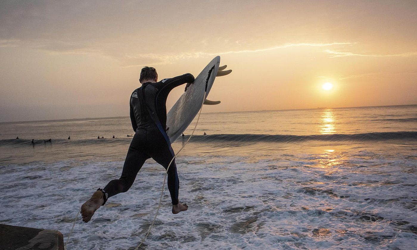 Surflari bat, uretara jauzi egiten, Hegoafrikako hondartza batean. KIM LUDBROOK / EFE.