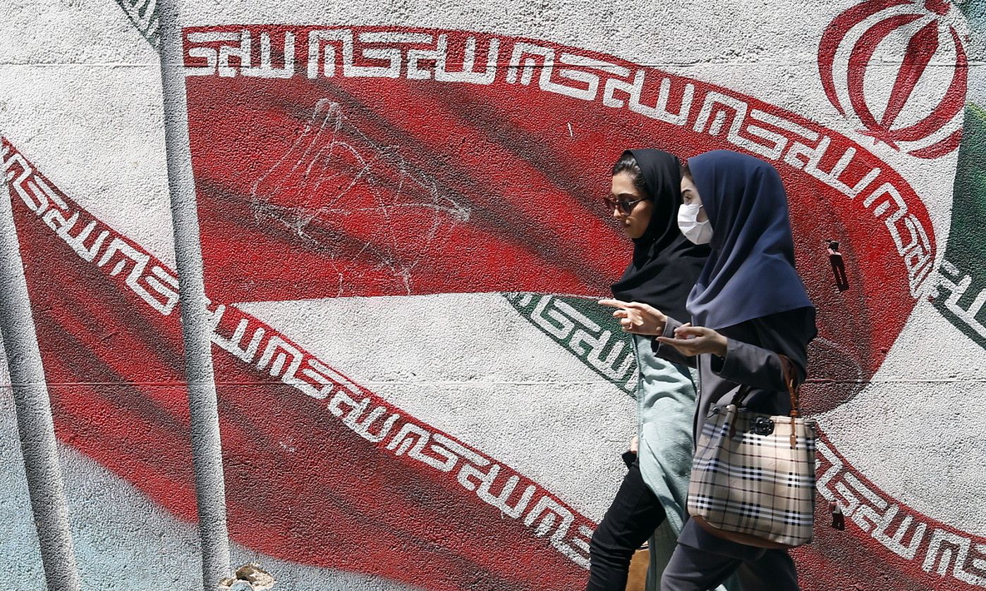 Bi emakume Irango banderaren aurretik igarotzen, abuztu hasieran, Teheranen. ABEDIN TAHERKENAREH / EFE.
