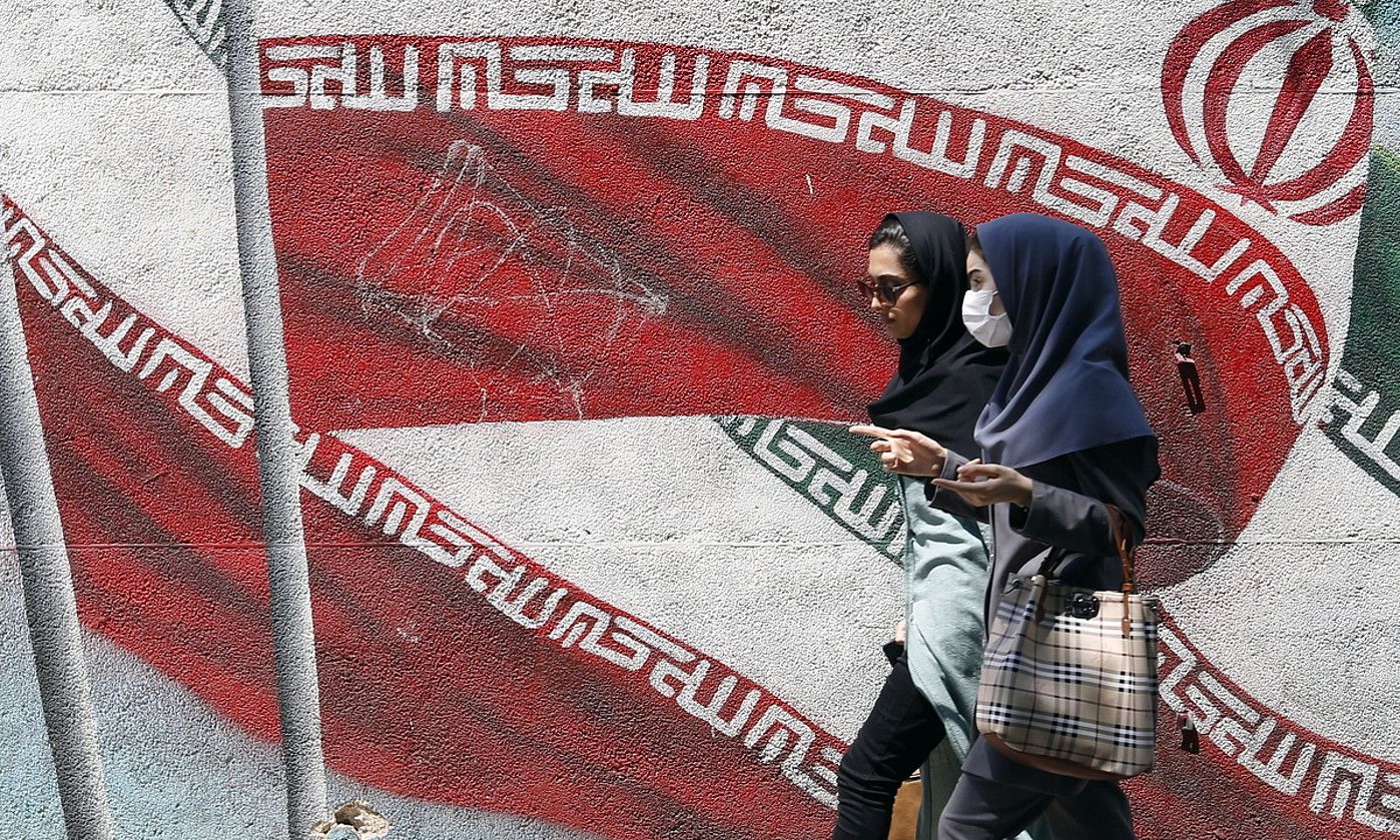 Bi emakume Irango banderaren aurretik igarotzen, abuztu hasieran, Teheranen. ABEDIN TAHERKENAREH / EFE. Bi emakume Irango banderaren aurretik igarotzen, abuztu hasieran, Teheranen. ABEDIN TAHERKENAREH / EFE.