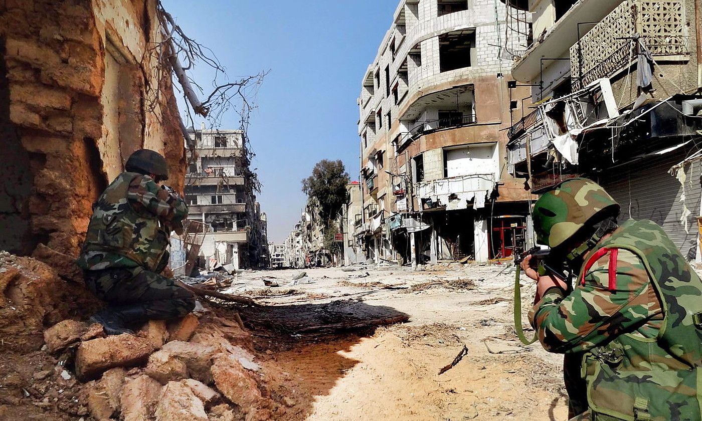 Siriako armadako bi soldadu, Darayako kale batean posizioa hartzen, 2013ko urtarrilean. EFE.
