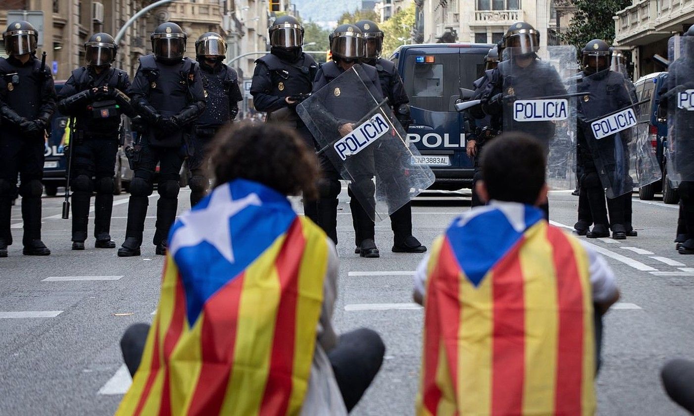 Bi manifestari, Espainiako Poliziaren aurrean, Bartzelonan, 2019ko urrian. ENRIC FONTCUBERTA / EFE.