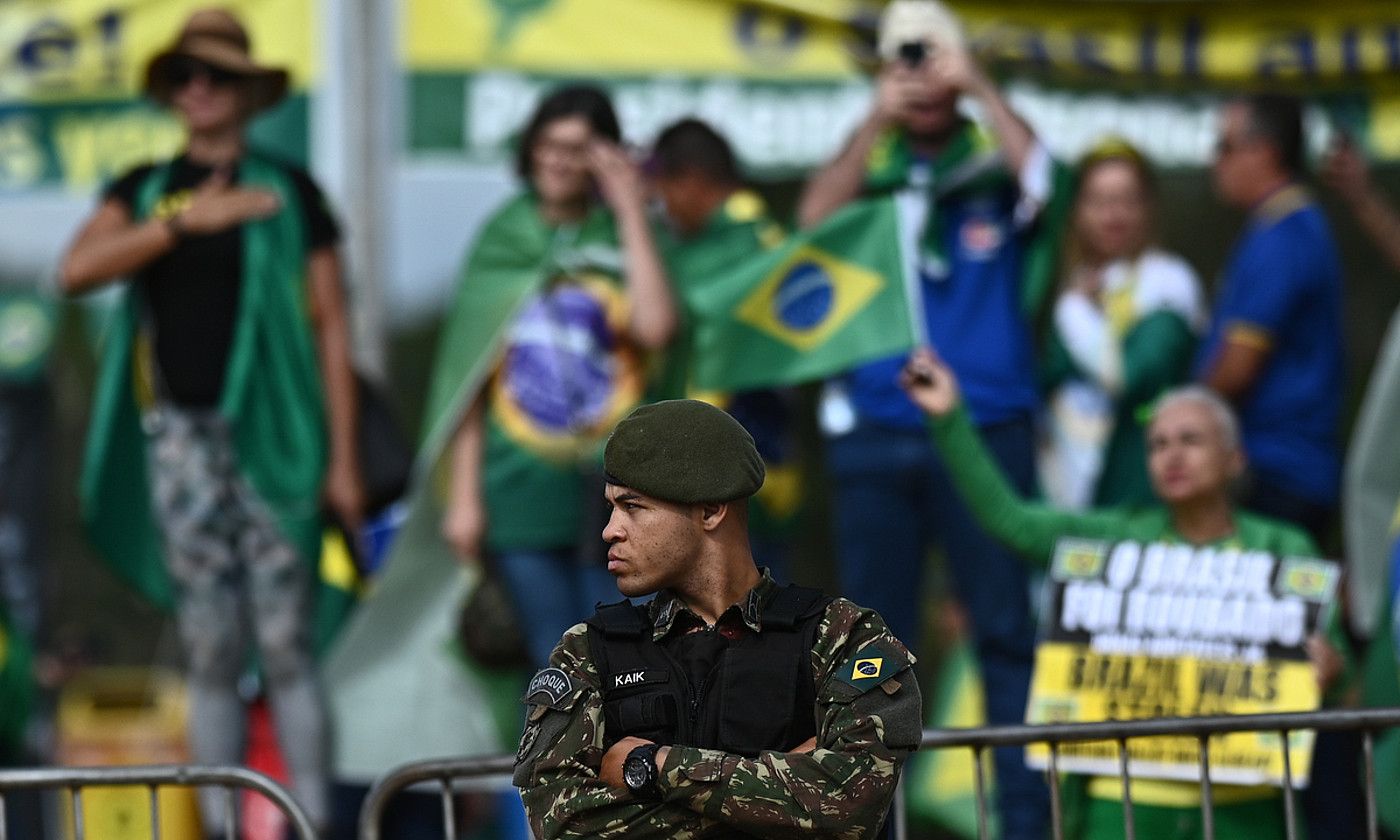 Brasilgo armadako soldadu bat Brasilian, atzean Bolsonaroren jarraitzaileak dituela. ANDRE BORGES / EFE. Brasilgo armadako soldadu bat Brasilian, atzean Bolsonaroren jarraitzaileak dituela. ANDRE BORGES / EFE.