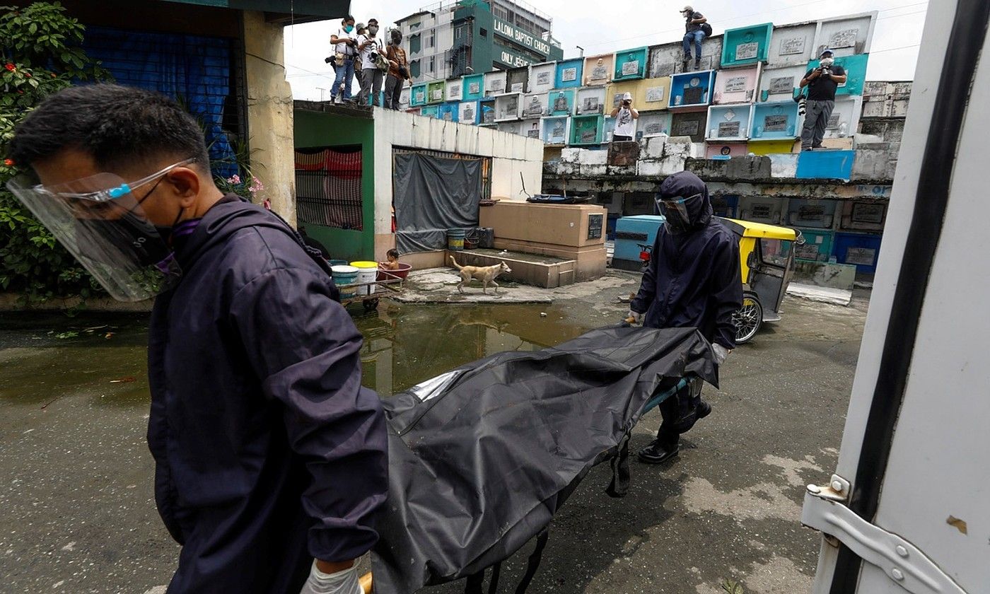 Ehorzketa etxe bateko bi langile, droga trafikatzailea zelakoan hil zuten pertsona baten gorpua eramaten, Manilan. EFE.