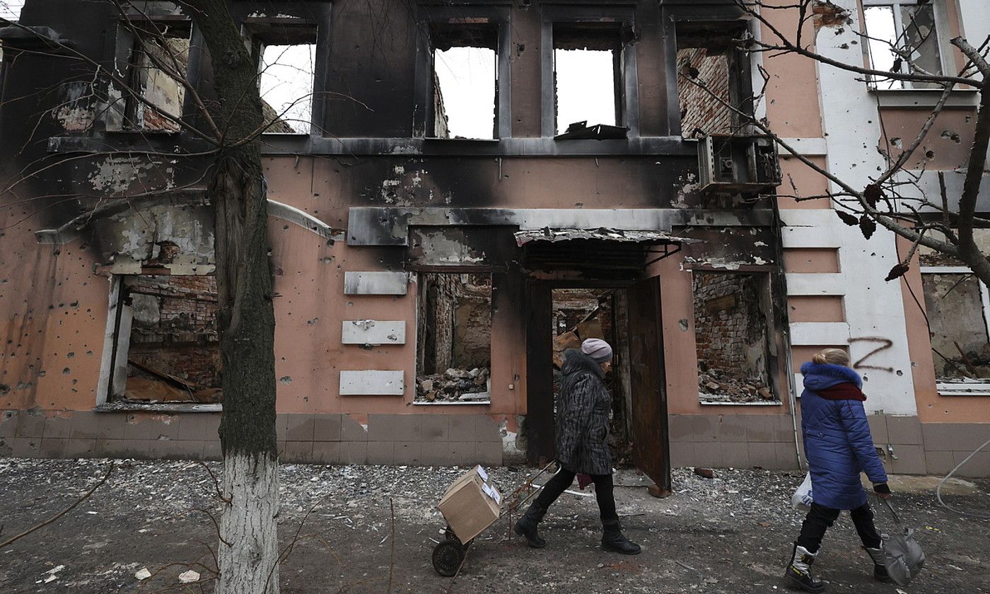 Bi pertsona bonbardatutako eraikin baten parean, joan den abenduan, Iziumen (Ukraina). SERGII KOZLOV / EFE.