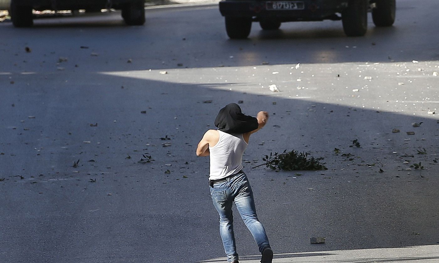Palestinar bat Israelgo armadaren bi ibilgailuren kontra harriak botatzen, atzo, Nablusen. ALAA BADARNEH / EFE. Palestinar bat Israelgo armadaren bi ibilgailuren kontra harriak botatzen, atzo, Nablusen. ALAA BADARNEH / EFE.