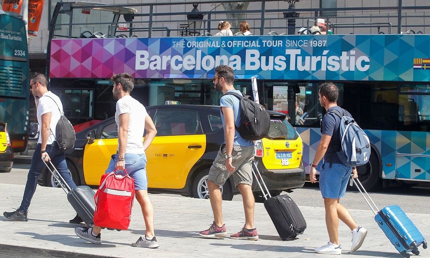 Turista batzuk Bartzelonan, atzean gida turistikoak ematen dituen autobusa dutela, 2019an. QUIQUE GARCIA / EFE.