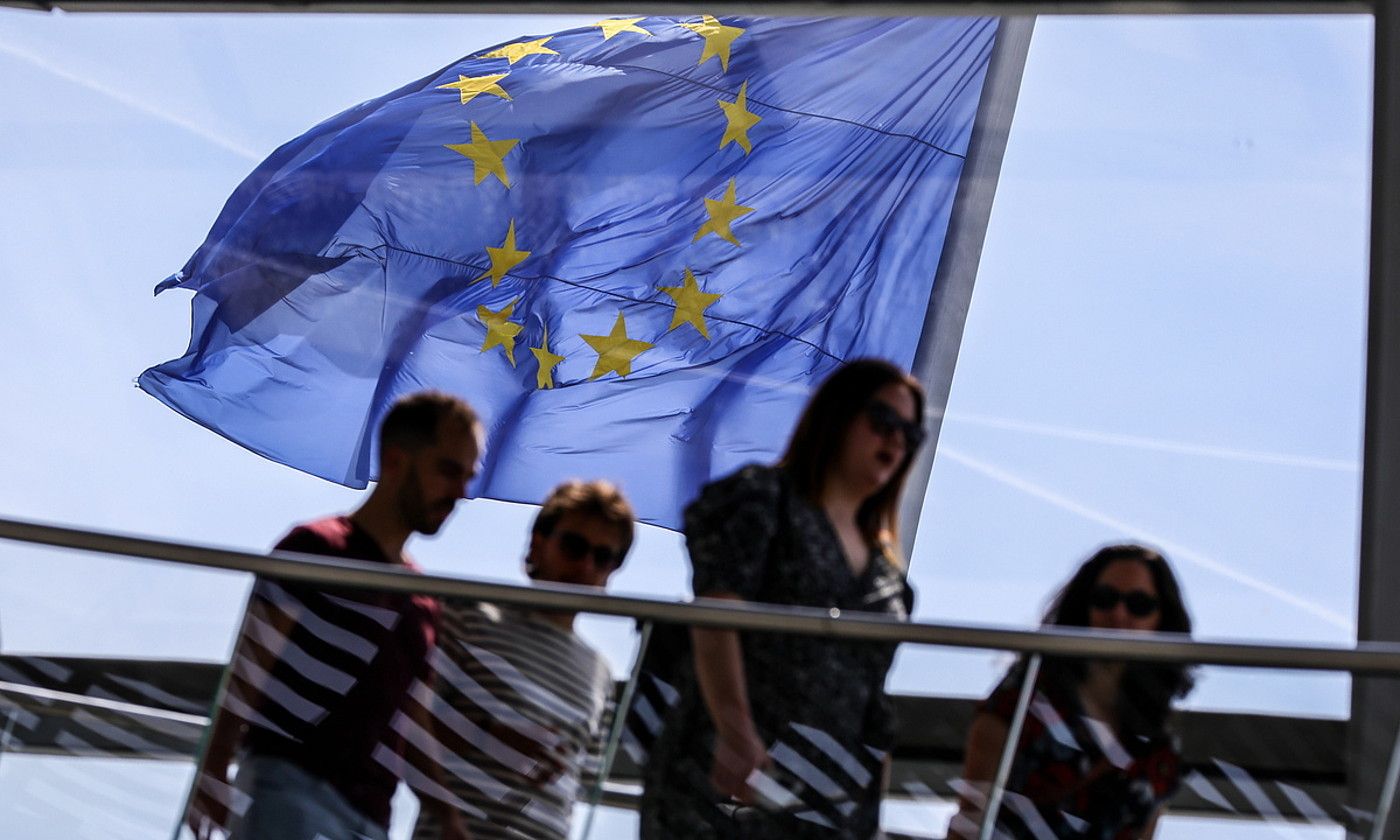 Pertsona batzuk Europako Batasunaren bandera baten aurretik pasatzen, Berlinen. OMER MESSINGER / EFE.