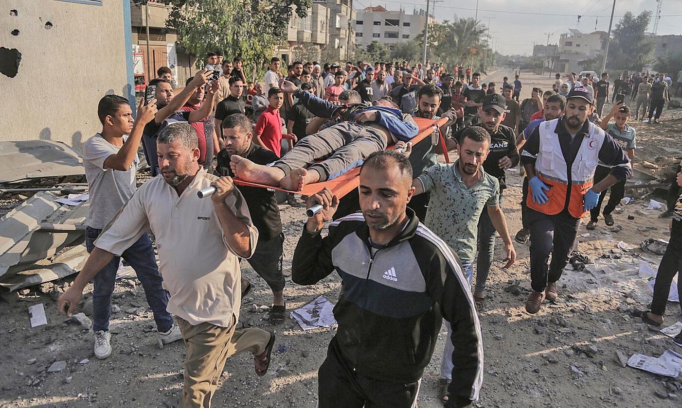 Palestinar batzuk Israelen bonbardaketa batek eragindako hondakinen artetik zauritu bat ateratzen, Gazako zerrendako Khan Yunis hirian, atzo. HAITHAM IMAD / EFE.