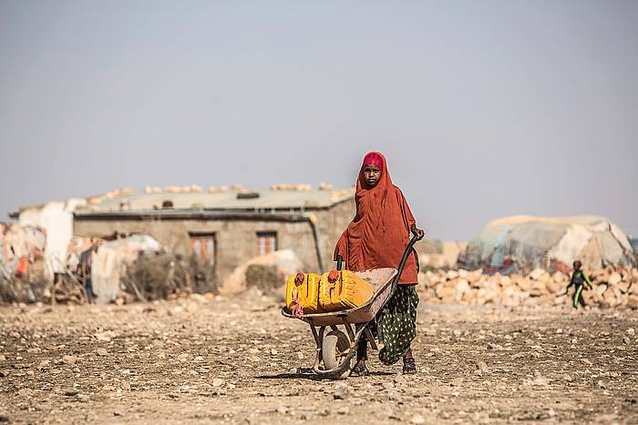 Neskatxa bat, ur bidoi bat garraiatzen, Somaliako herri batean. PABLO TOSCO, EFE