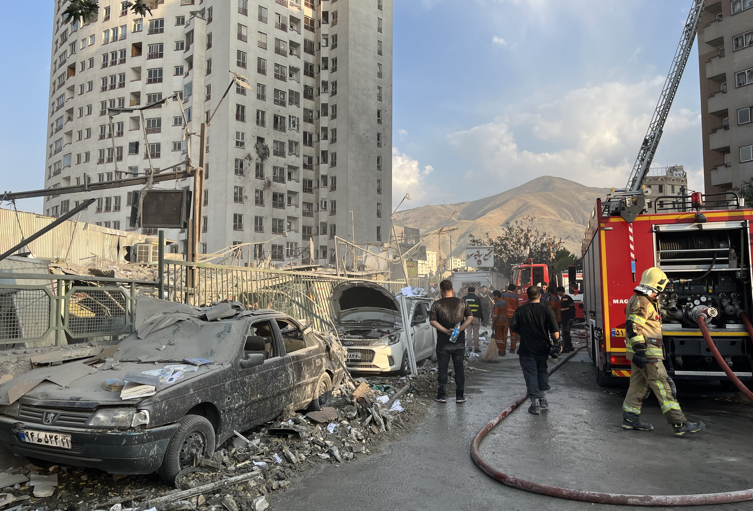 Suhiltzaileak Teheran iparraldeko bizitoki batean, Israelen erasoak eragindako suak itzaltzen. ABEDIN TAHERKENAREH / EFE