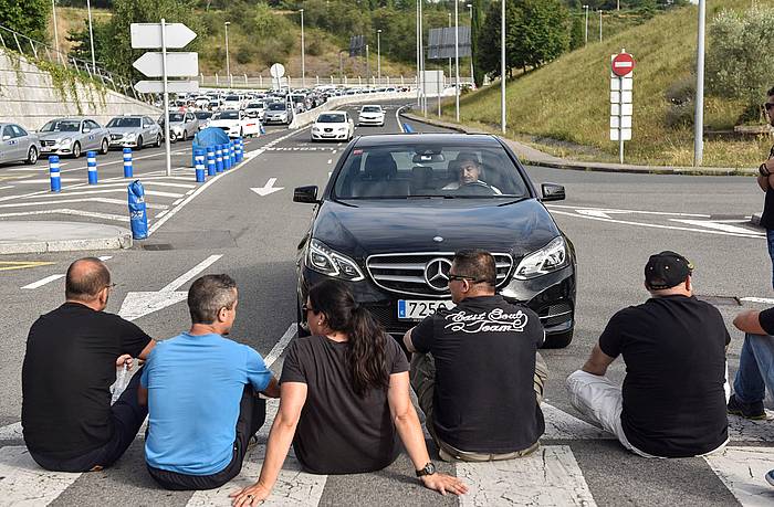 Bilboko taxi gidari talde bat Uber eta Cabify enpresen jardunaren kontra protestan, iazko uztailean, Bilboko aireportuan. MIGUEL TOñA, EFE