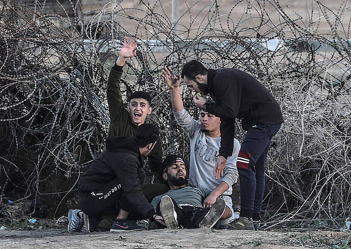 Palestinar maifestariak laguntza eskatzen, soldadu israeldarrek kide bat zauritu ondoren, gaur, Gazako mugan eginiko protesta batean. MOHAMMED SABER / EFE