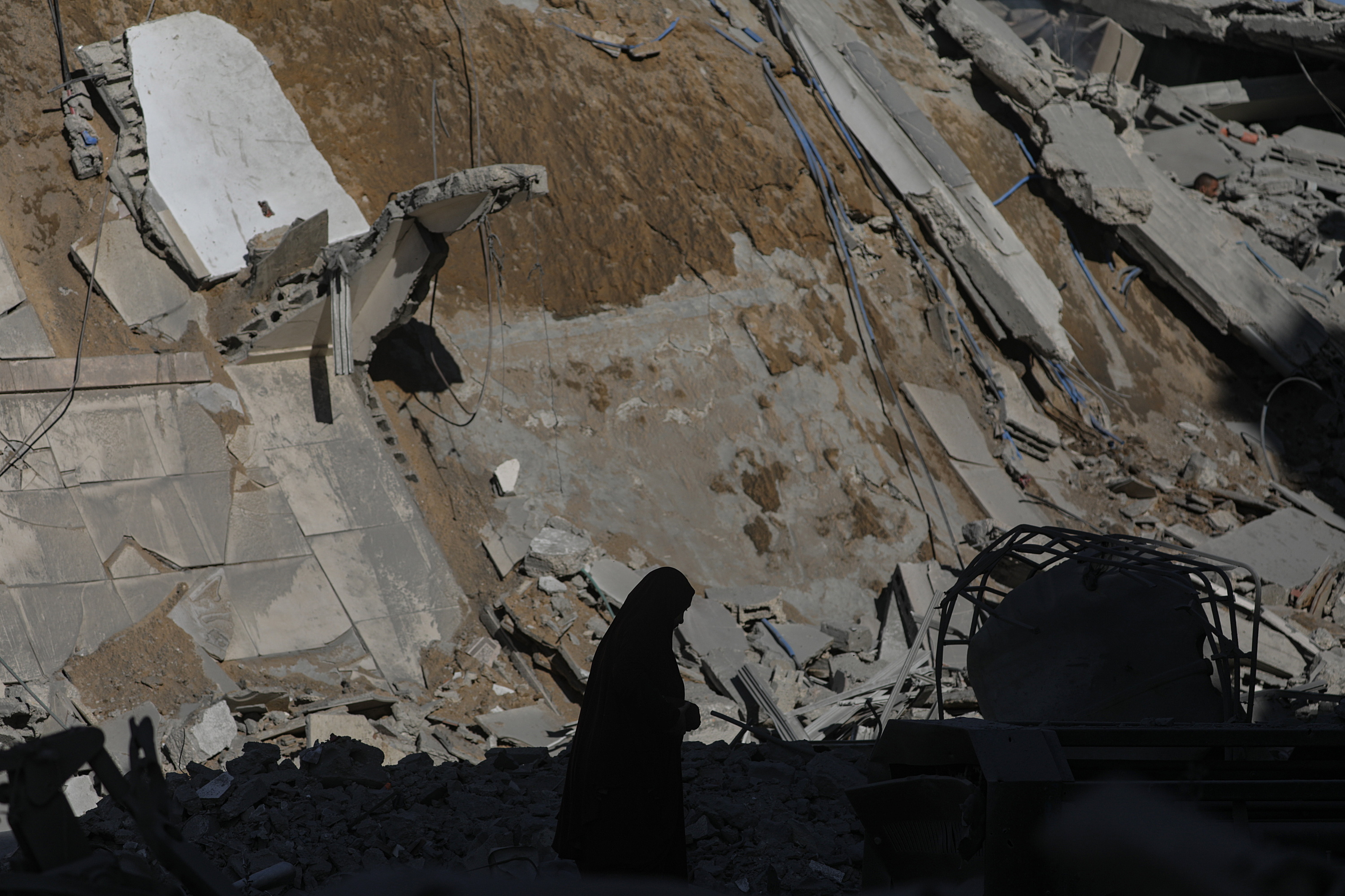Emakume palestinar bat etxebizitza birrindu batean hondakinak jasotzen, atzo, Gaza hirian. MOHAMMED SABER / EFE