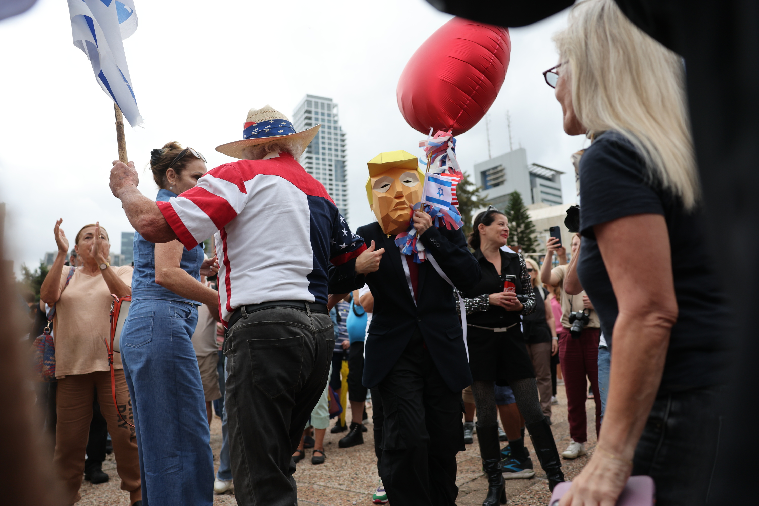 Israeldar bat Donald Trumpen maskara jantzita bake-planaren lehen fasea ospatzen Israeldar bat Donald Trumpen maskara jantzita bake-planaren lehen fasea ospatzen