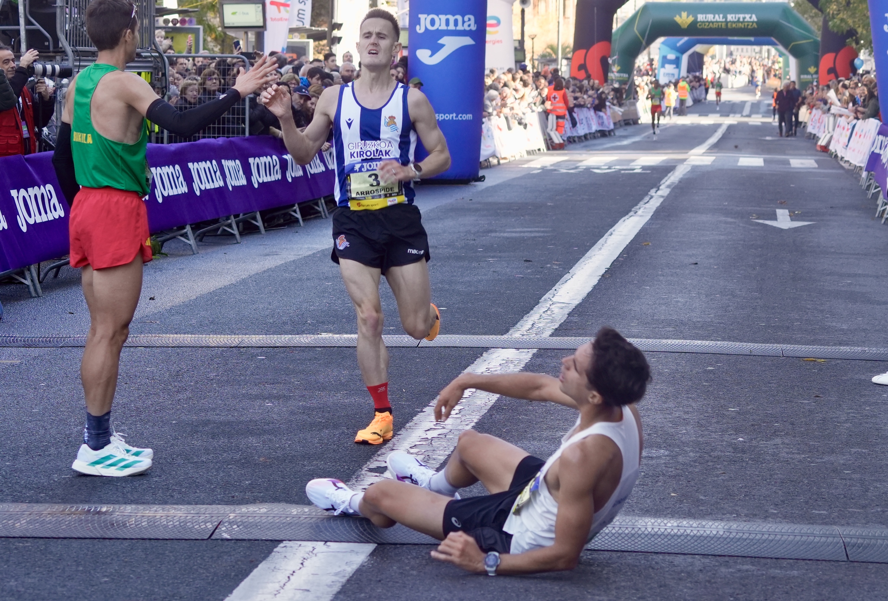 Lasterketako lehen hiru gizonezkoak helmugara iritsi berri: Celada Arrospideri eskua ematen, eta Mentrida, lurrean. ANDONI CANELLADA / FOKU