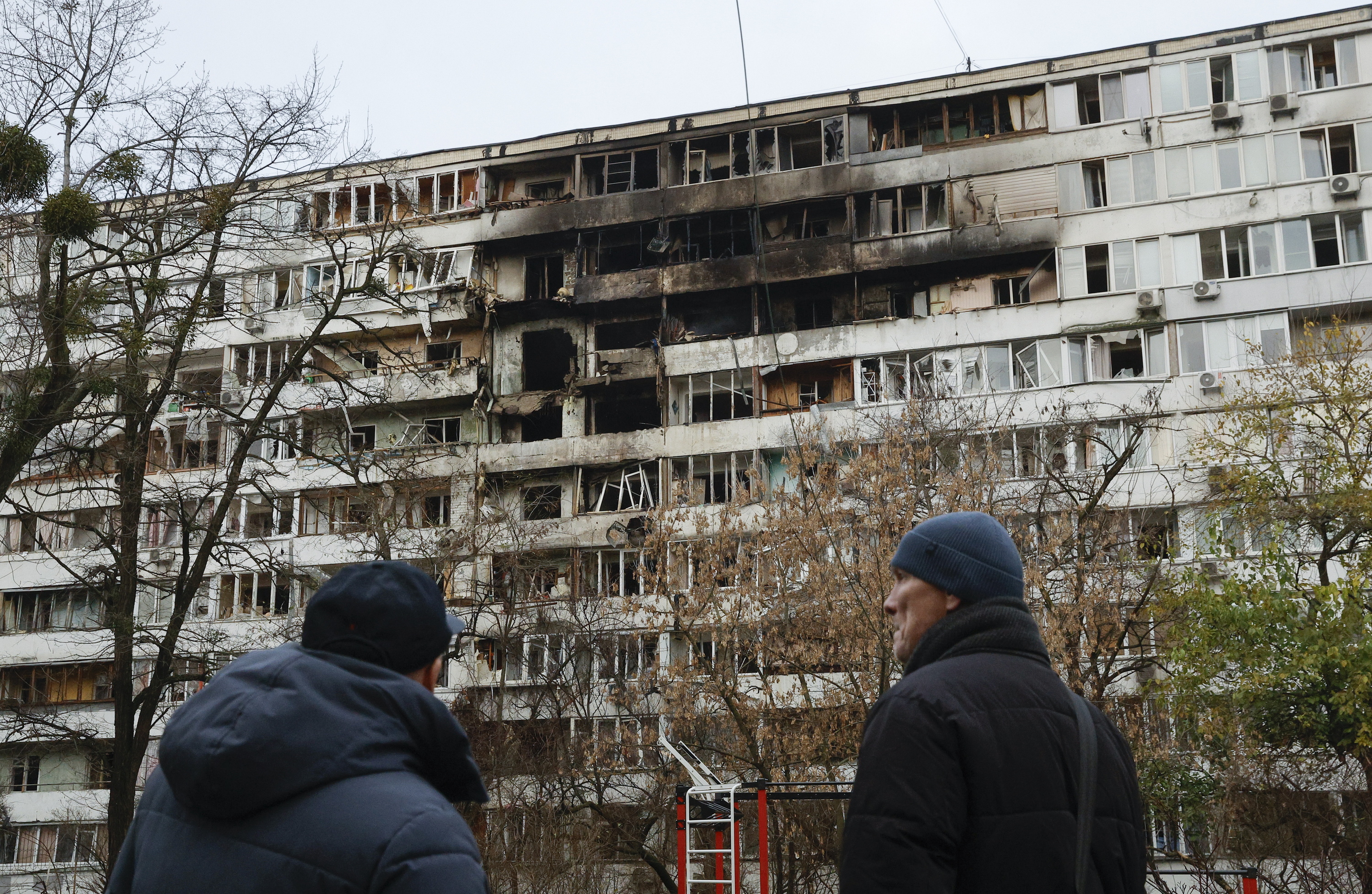 Bi pertsona gaur Kieven, Errusiaren erasoak jotako etxebizitza bloke bati begira. SERGEI KOZLOV / EFE