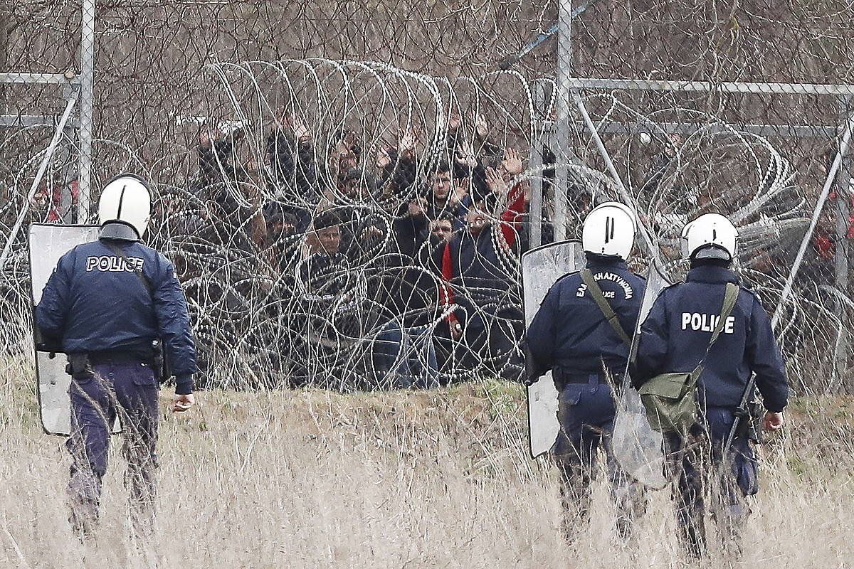 Greziako polizia Turkia eta Grezia arteko muga zaintzen, eta, hesiaren beste aldean, Siriako gerratik ihesi joandako errefuxiatu talde bat. DIMITRIS TOSIDIS, EFE