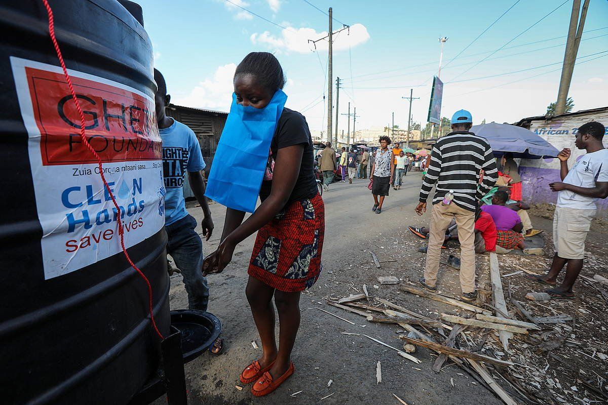 Emakume bat eskuak garbitzen, GKE batek errepidean utzitako ura eta xaboia baliatuz, Nairobin. DANIEL IRUNGU / EFE