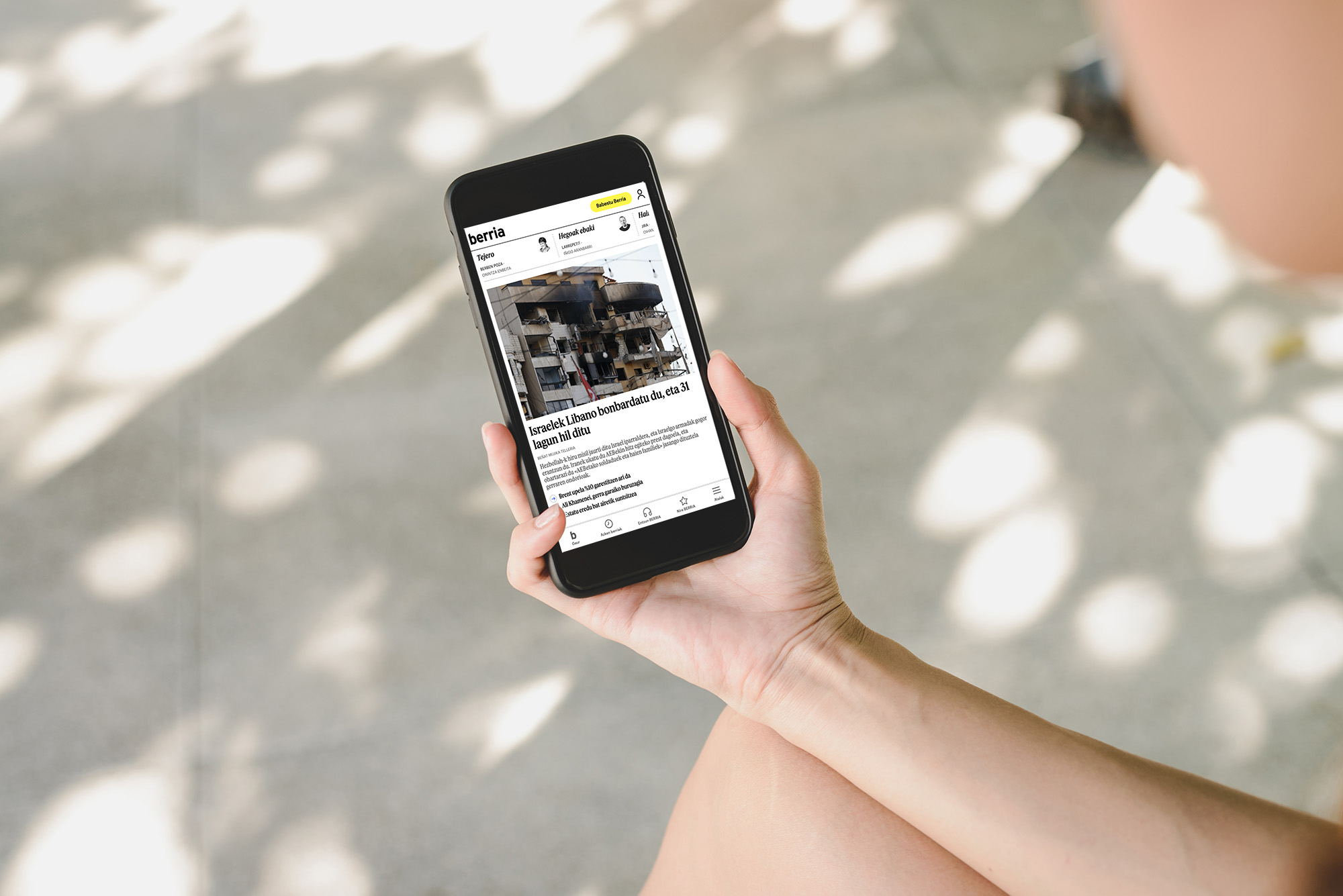 Herritar bat sakeleko telefonoan BERRIAren albisteak irakurtzen. BERRIA