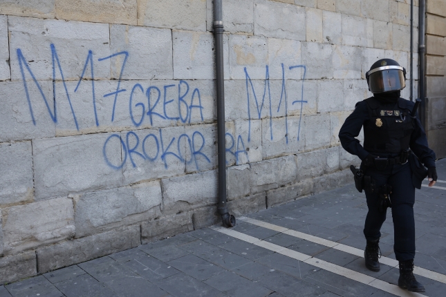 Espainiako Polizia bat grebaren aldeko aldarria egiten duen horma baten alboan, JESUS DIGES / EFE