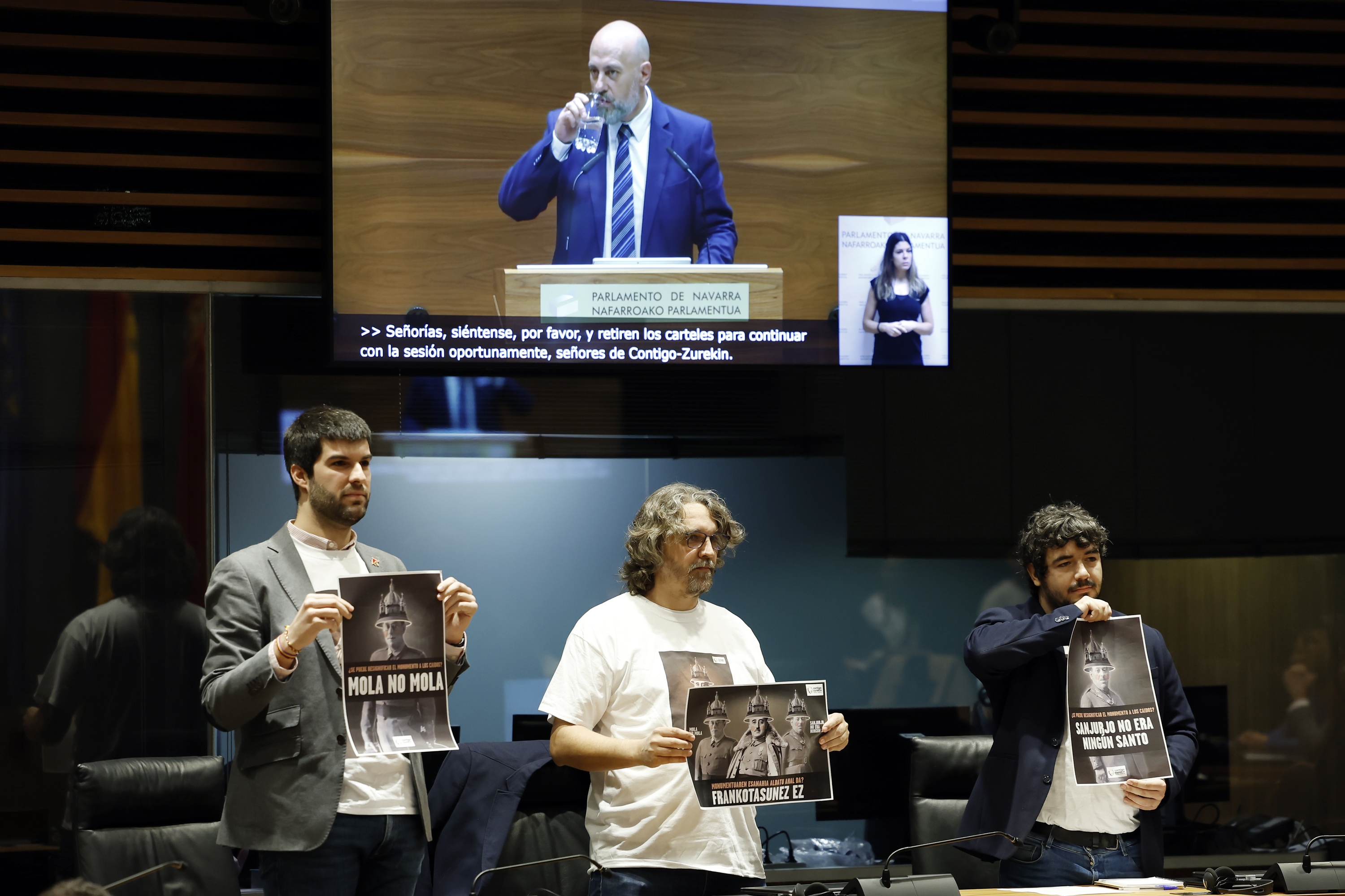 Zurekin Nafarroako hiru parlamentariak —Carlos Guzman, Daniel Lopez eta Miguel Garrido— Erorien Monumentua eraistearen aldeko kartelak eskuetan, 2024an. JESUS DIGES / EFE