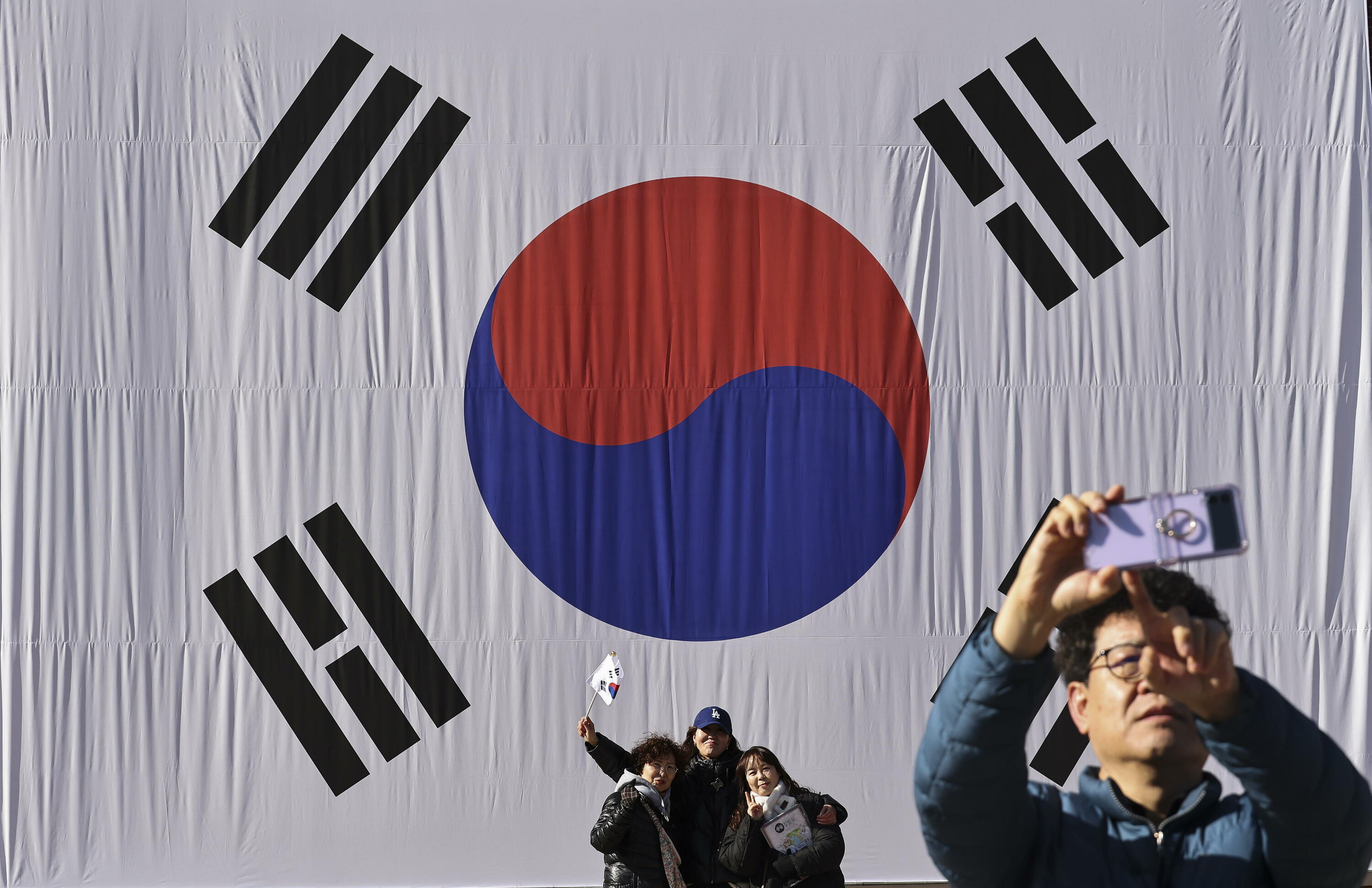 Pertsona batzuk Hego Korearen banderaren aurrean argazkiak egiten Seulen, artxiboko argazki batean. JEON HEON-KYUN / EFE