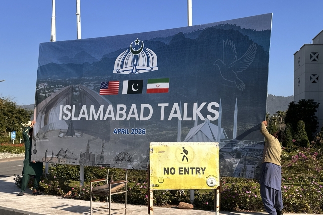 Langile batzuk bilera iragartzeko kartel bat kentzen, gaur, Islamabaden. SOHAIL SHAHZAD / EFE