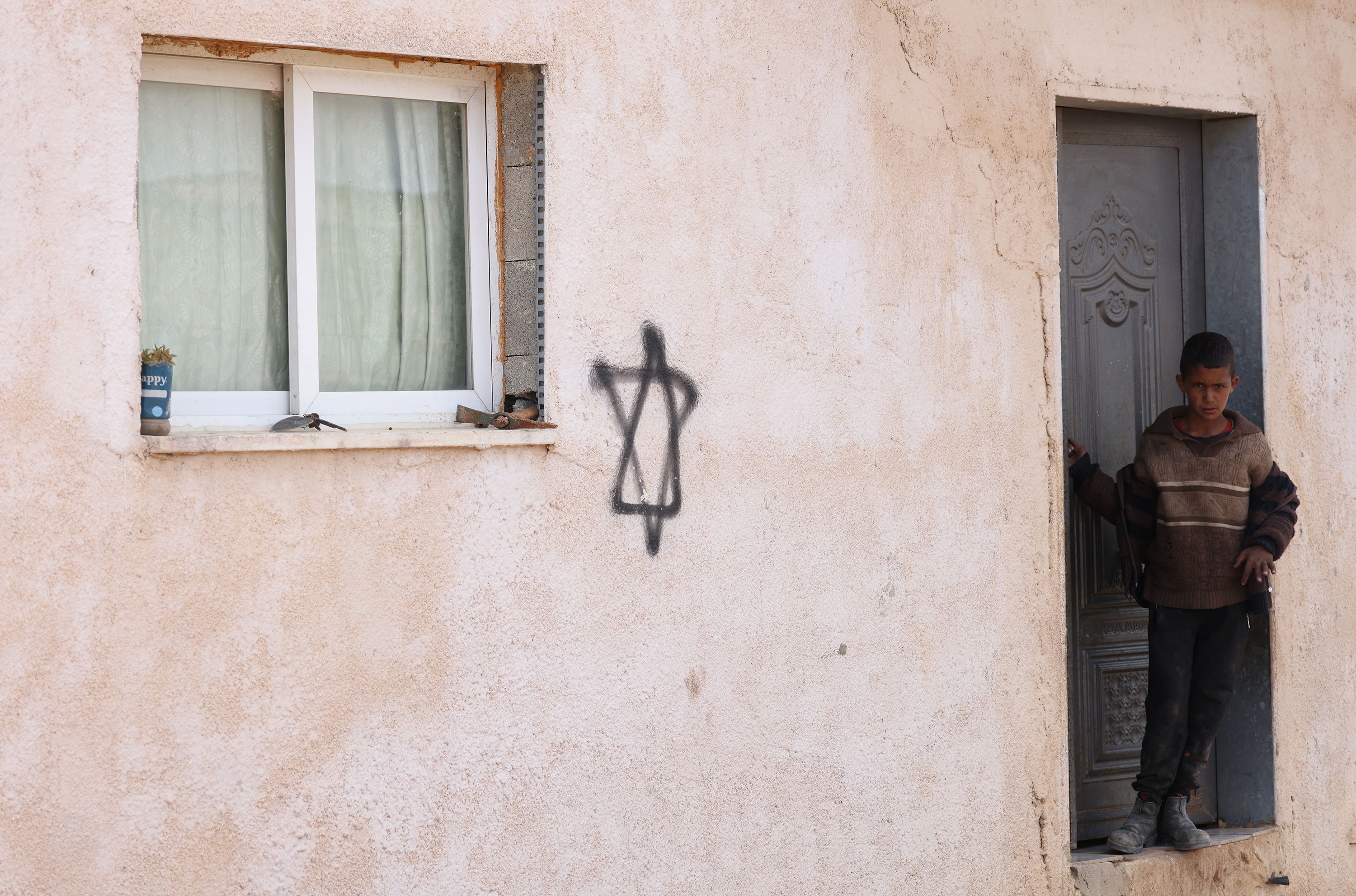 Haur palestinar bat, kolono israeldarrek pintatutako Daviden izar baten alboan, apirilaren 6an, Nablusetik hurbil. ALAA BADARNEH / EFE