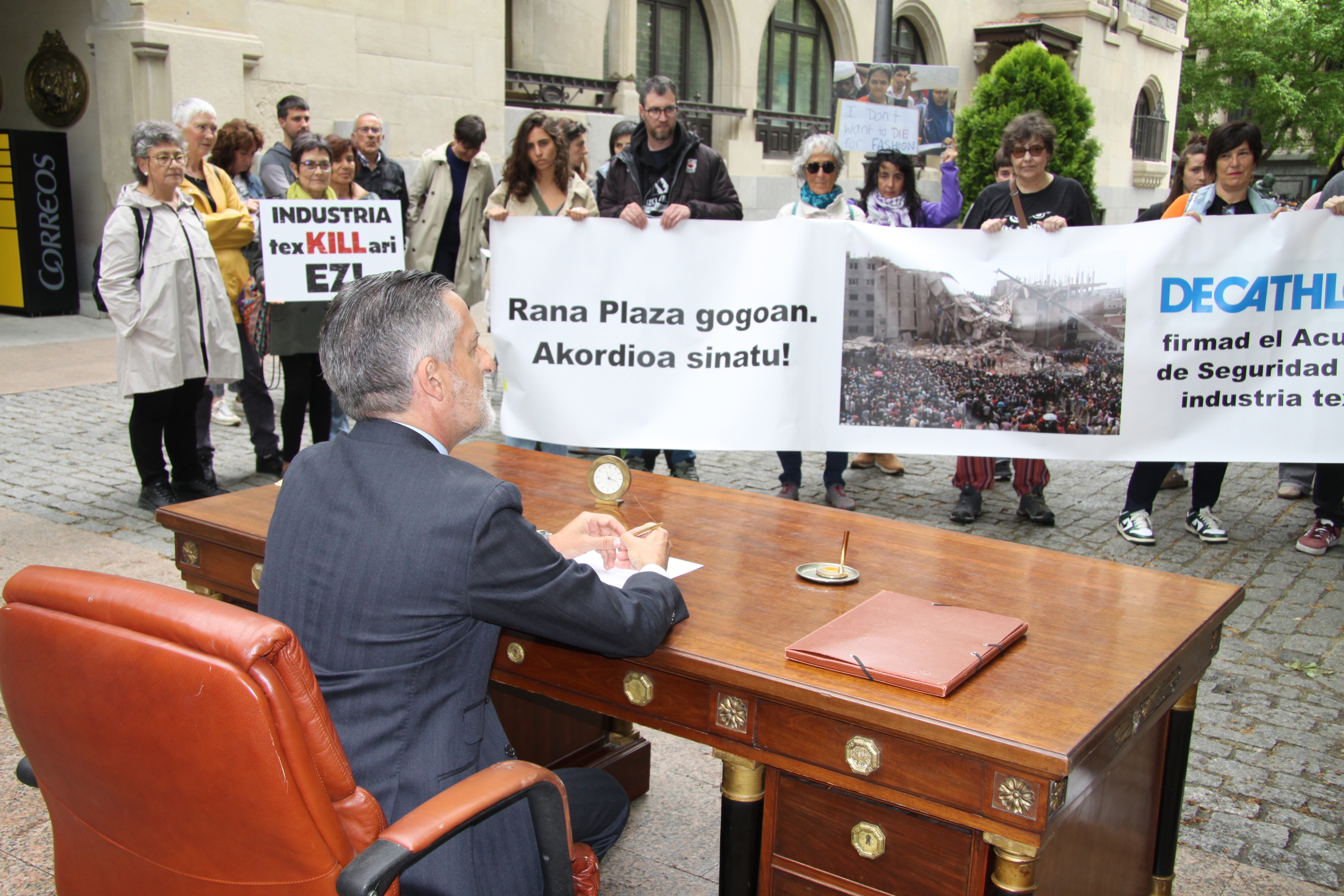 Gasteizko Urrezko Zeledonen plazan egindako performancea; manifestariek estu hartu dute zuzendaria, dokumentua sina dezan. SETEM HEGO HAIZEA