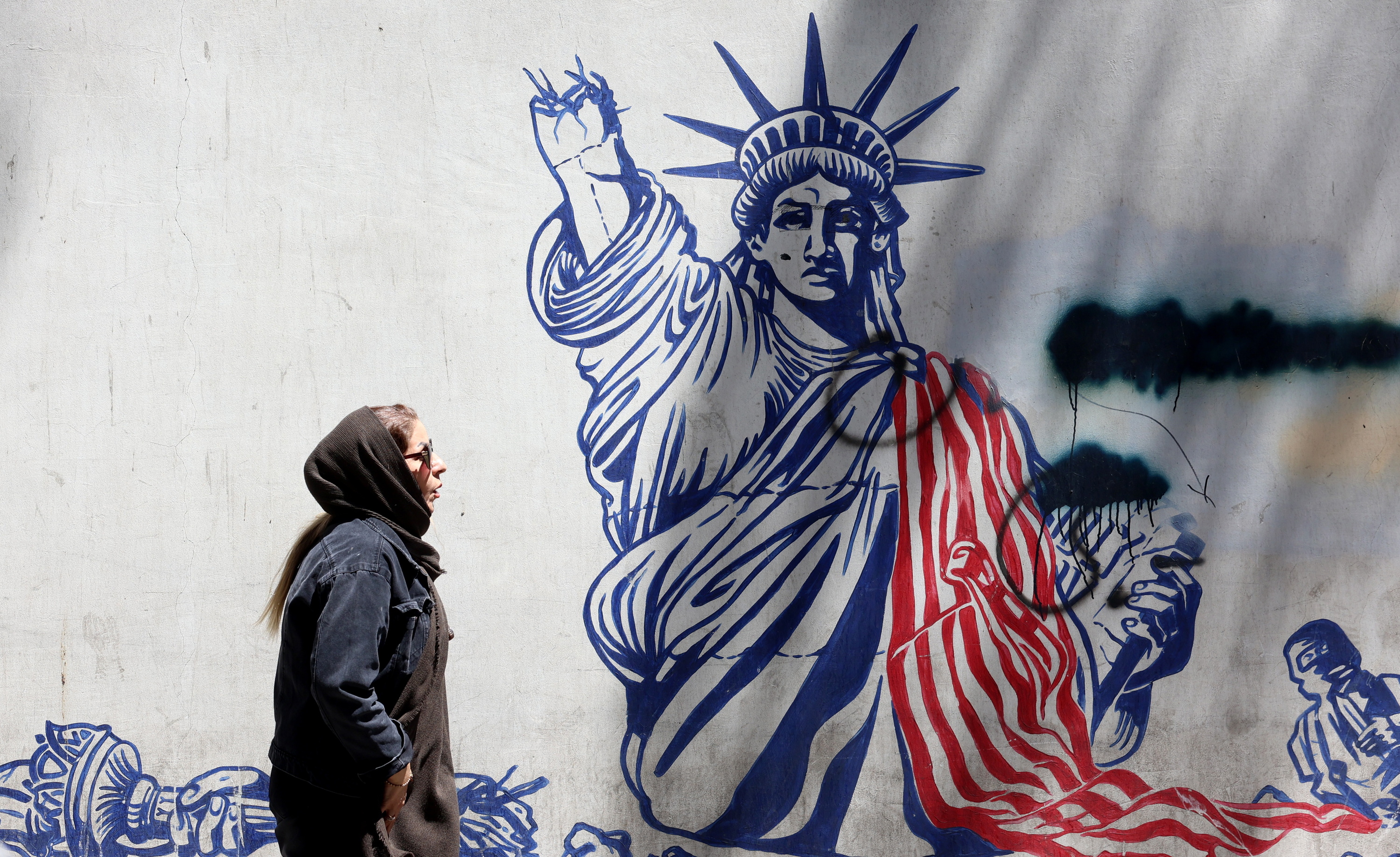 Emakumezko bat gaur Teheranen, AEBen kontrako mural baten aurretik igarotzen. ABEDIN TAHERKENAREH / EFE